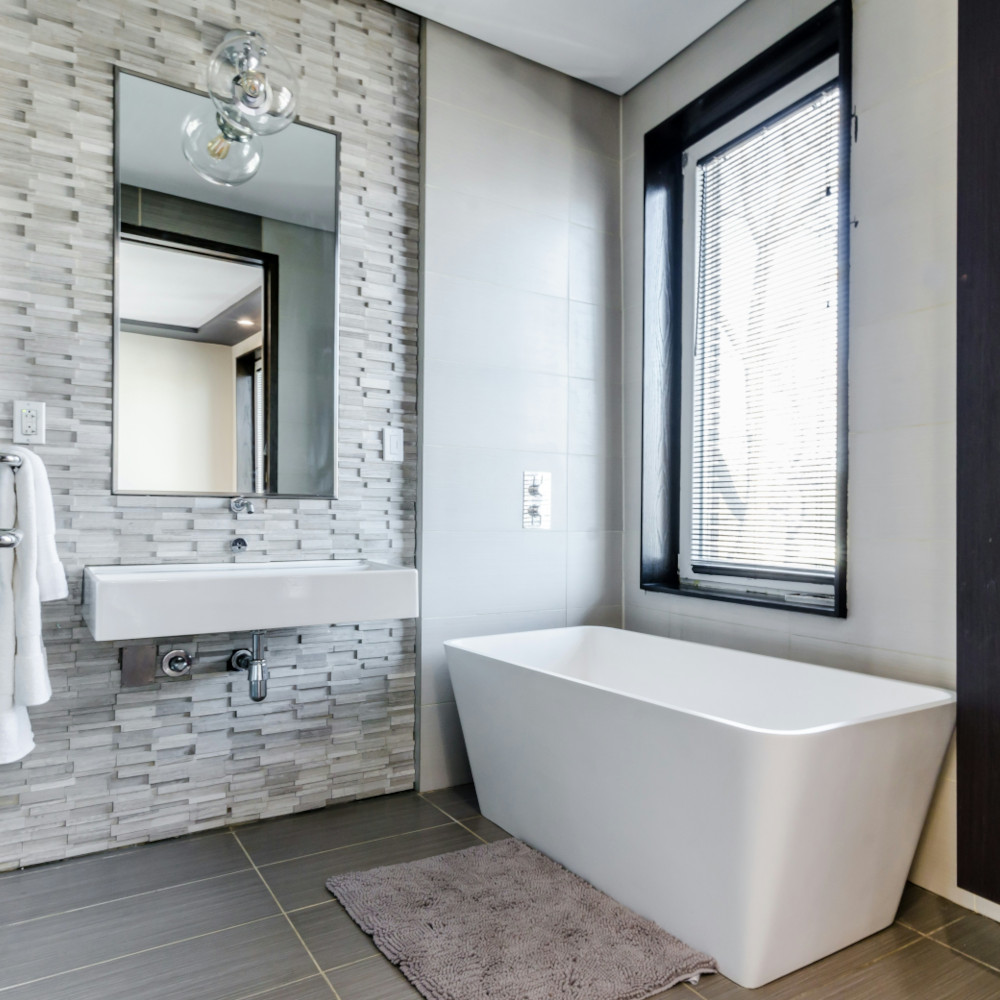 Ein helles, schön renoviertes Badezimmer mit viel Tageslicht, moderner Badewanne und weiteren Ausstattungen.