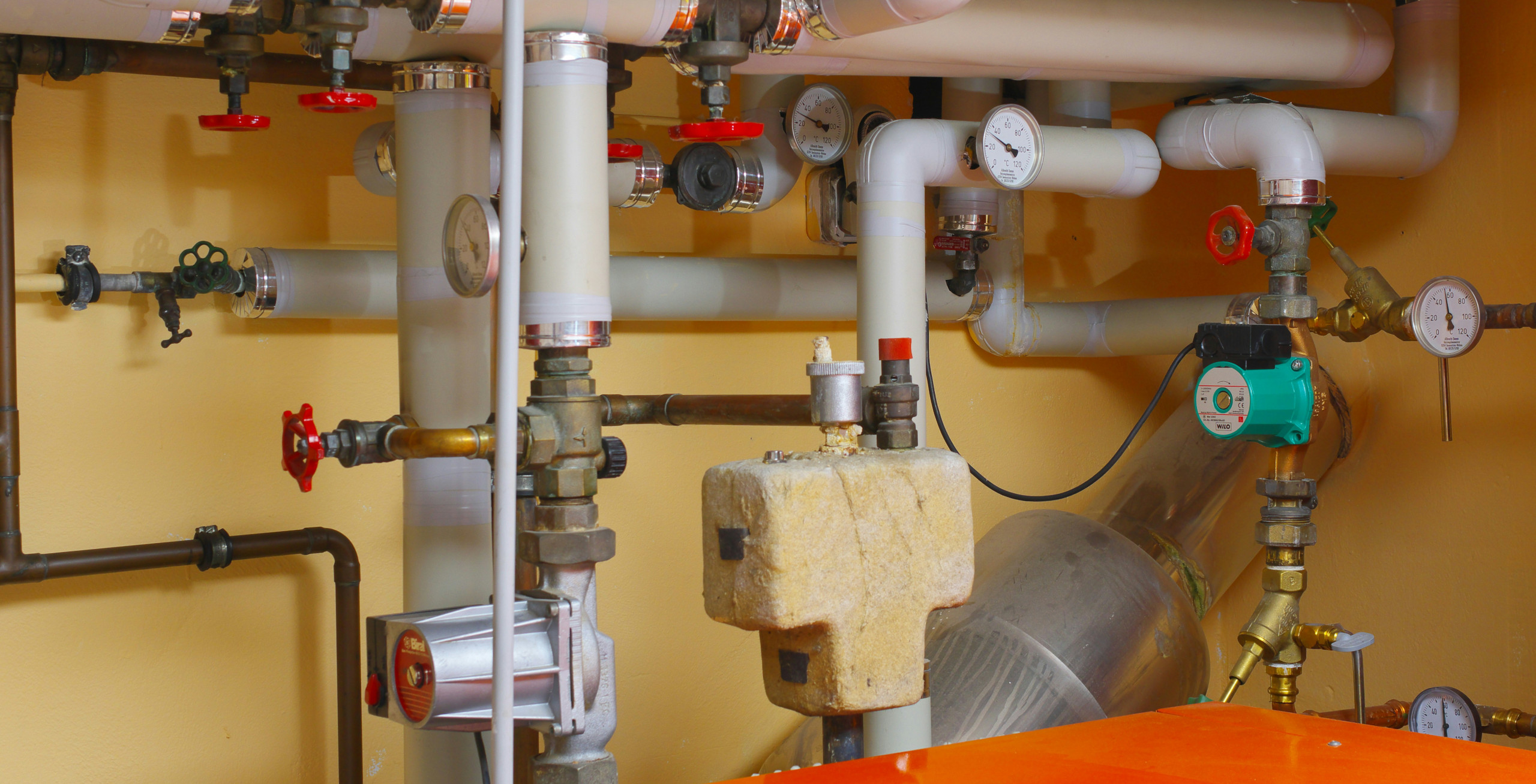 Sauber angeordnete und installierte Heizungsrohre und Pumpen in einer technischen Anlage.