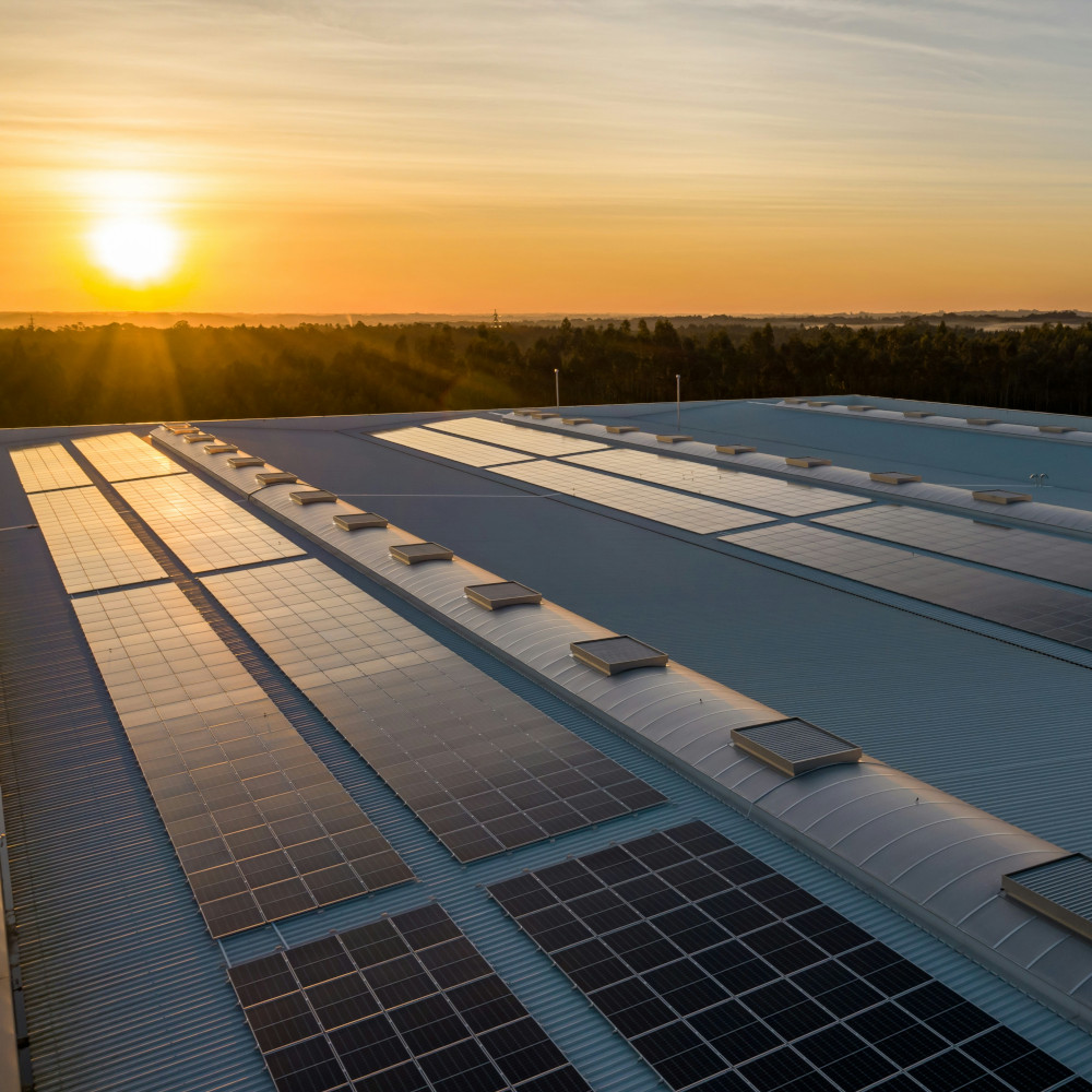 Solarthermieanlage auf einem Hausdach bei Sonnenuntergang, mit der Sonne am Himmel.