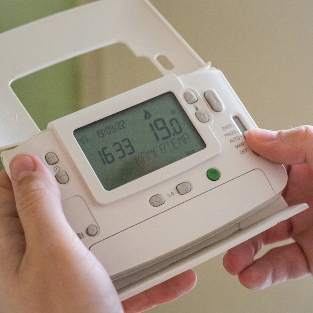 Digitales Thermostat für die Heizungssteuerung, das in den Händen gehalten wird.